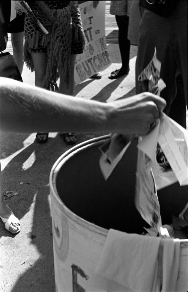 A demonstrator's arm throwing the torn pages of a magazine into the 'Freedom Trash Can' on the Atlantic City Boardwalk during a protest against the Miss America beauty pageant, Atlantic City, 1968.