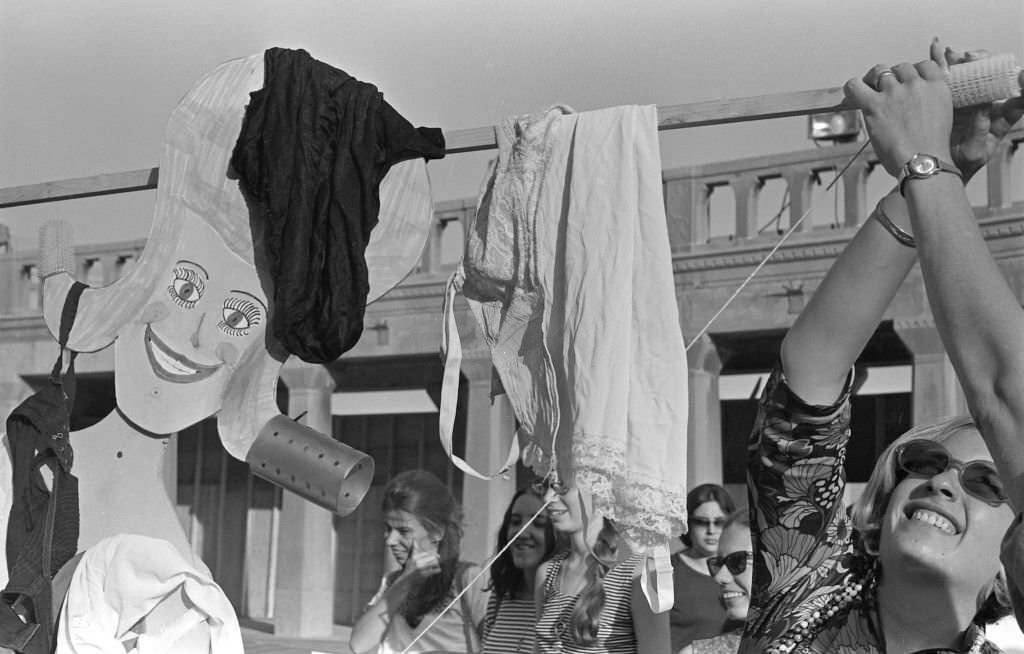 A demonstrator holds up a Miss America marionette draped in underwear, high heels, and hair curlers during a protest of the Miss America beauty pageant, Atlantic City, 1968.
