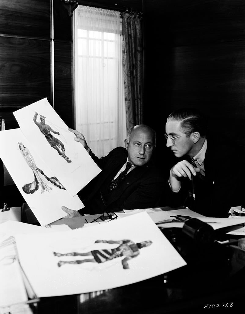 Filmmaker Cecil B DeMille inspecting costume design ideas for the film 'Samson and Delilah'