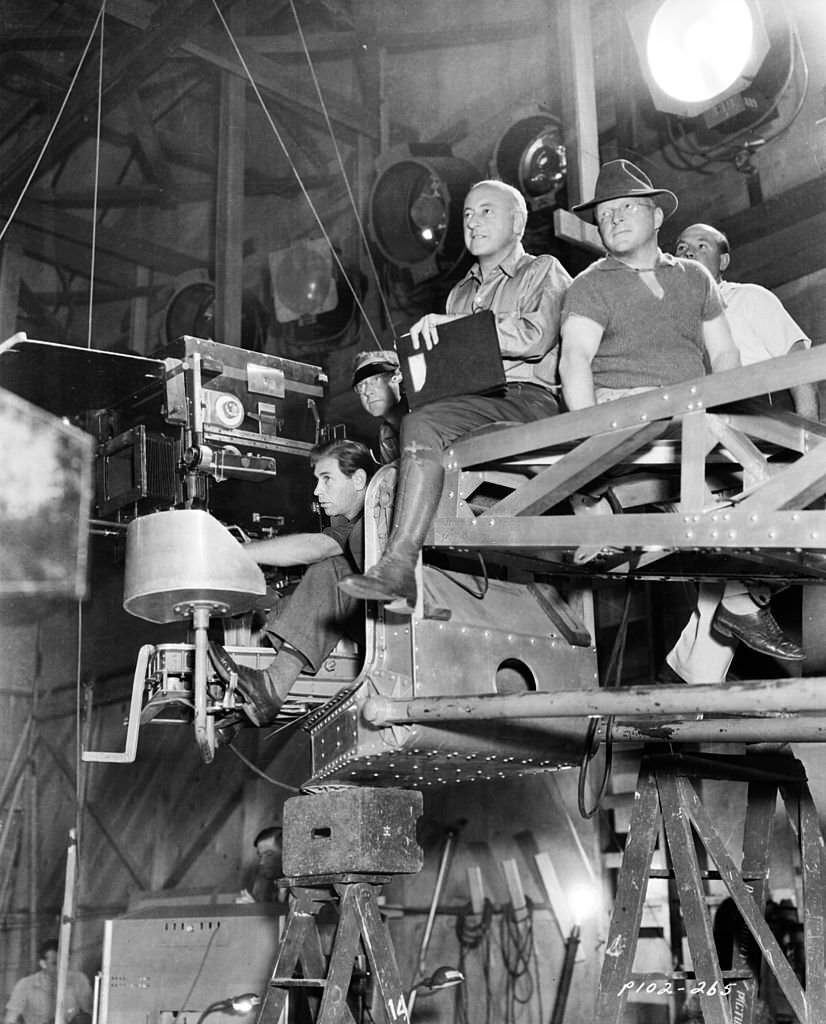 Cecil B DeMille sitting on a camera rig with members of his crew, on the set of the film 'Samson and Delilah', 1949