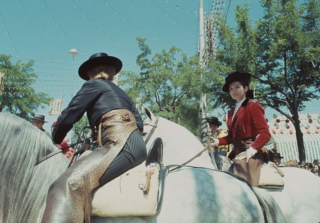 Former First Lady of the United States, Jacqueline Kennedy wearing a picador style jacket and brimmed hat whilst riding a white horse at the Seville Fair in Spain in April 1966.