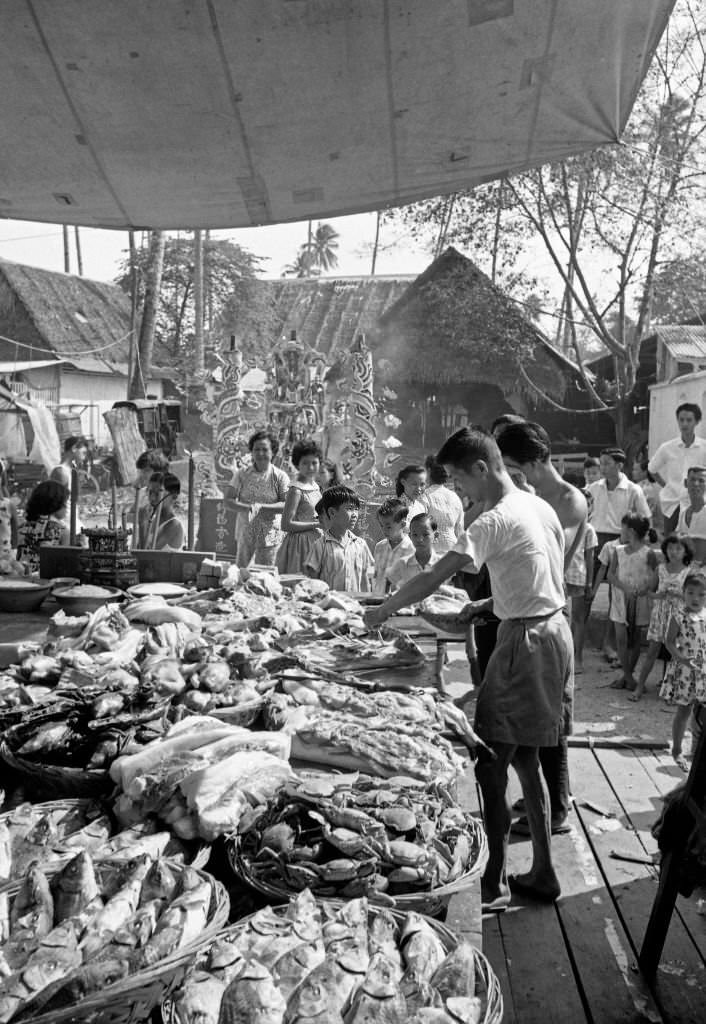 People waiting in a line in front of a fish stall, Singapore, 1962
