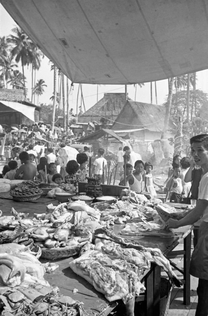 Man cutting the meat displayed on his stall, Singapore, 1962