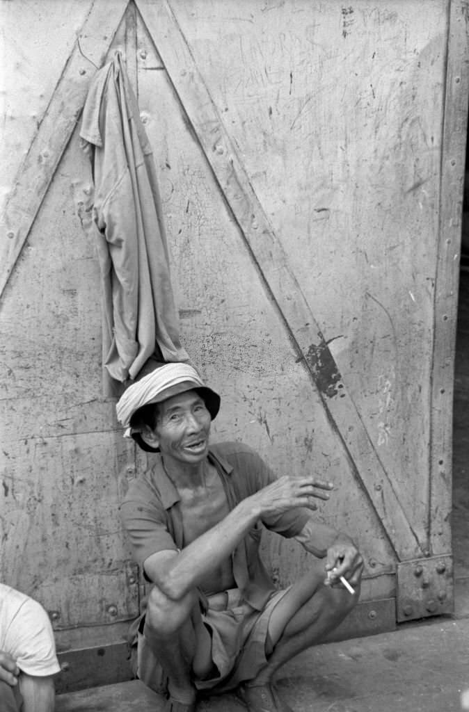 Asian man posing smiling with a cigarette in the hand. Singapore, 1962