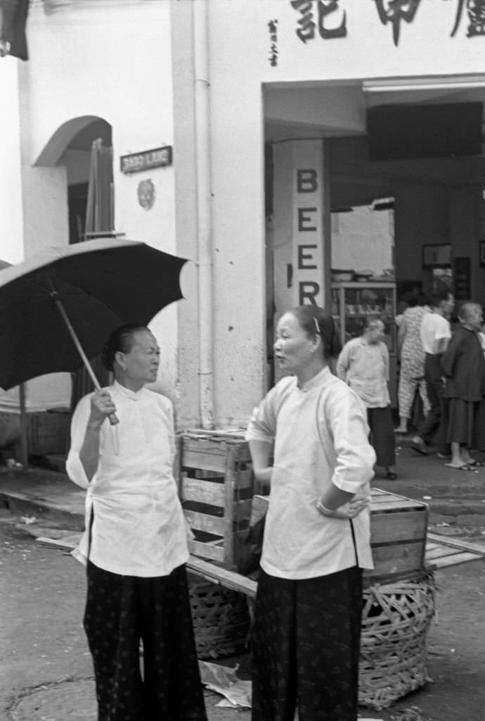 Two Asian women chatting outside a shop in Singapore, 1962