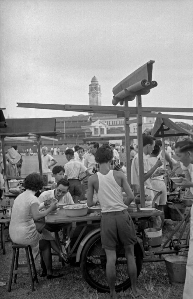 People eating street food sitting at a kiosk, Singapore, 1962