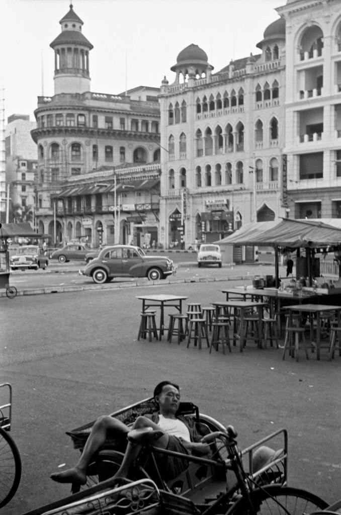 Asian man sleeping lying into his rickshaw, Singapore, 1962