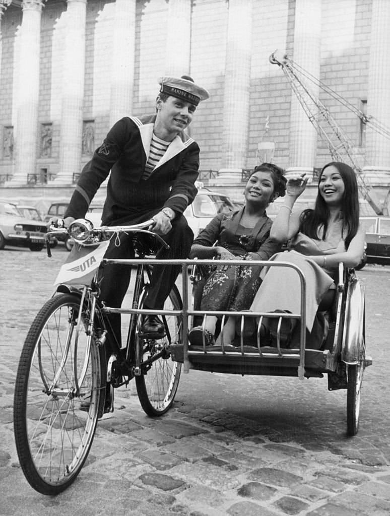 A French sailor takes two ladies from the Singapore Tourist Office on a jaunt around Paris in a trishaw, 1971