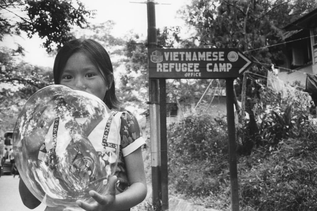 A little girl blowing bubbles at Hawkins Roadd Vietnamese refugee camp in Singapore, July 28, 1979.