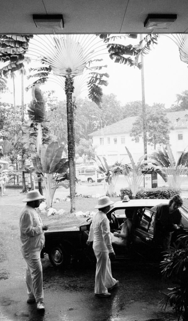 Two valets in colonial-inspired white suits welcoming guests to the Raffles Hotel, 1989