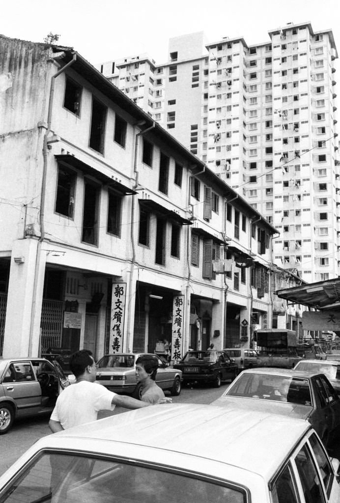 The high-rise Kreta Ayer Complex (renamed the Chinatown Complex in 1984) looms above shophouses on Sago Lane, Chinatown, Singapore, 1983.