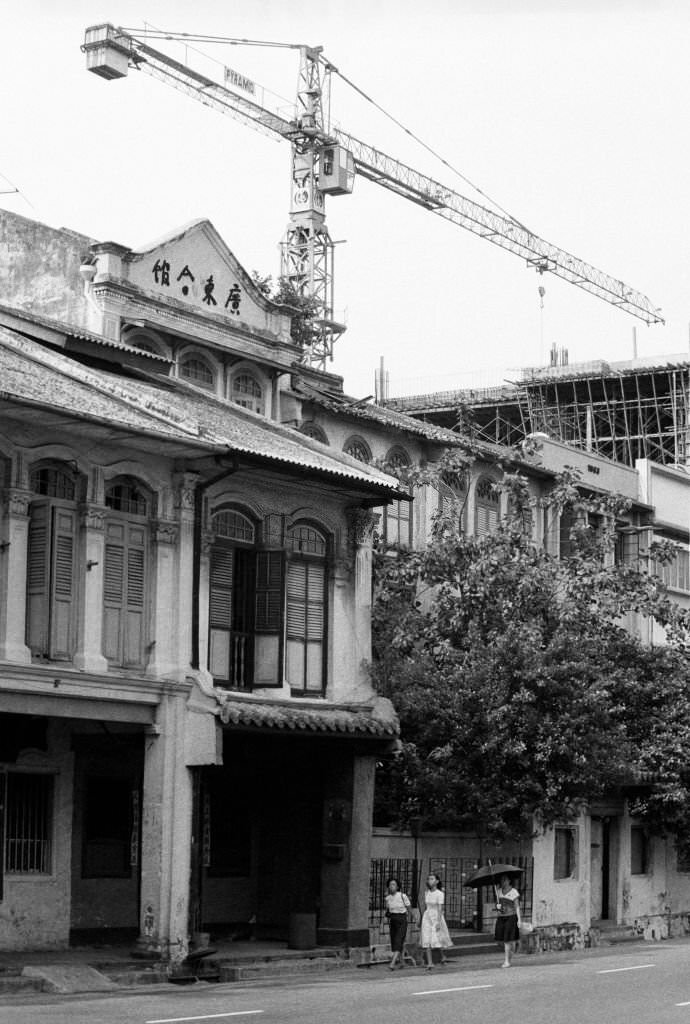 A crane aids construction of Chinatown Plaza on the corner of Neil Rd and Craig Rd, while authentic shophouses on Neil Rd await a conservation order Chinatown, Singapore, 1983