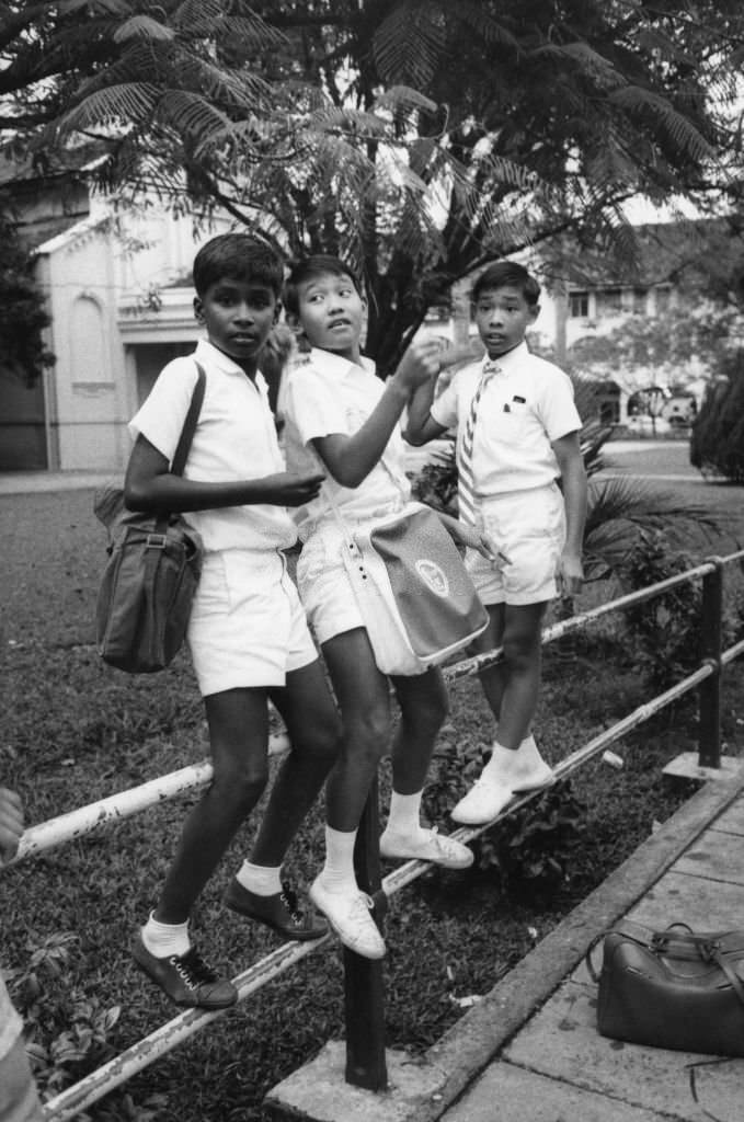 Schoolchildren perched on a fence in Singapore, March 1981.