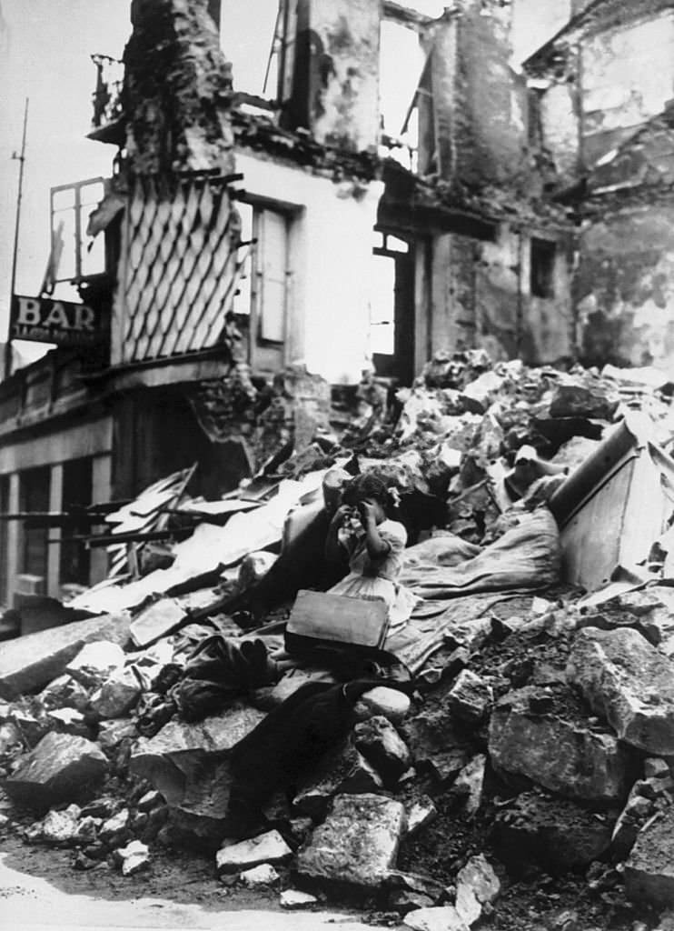 During the Spanish civil war, a young girl is crying and sitting in front of the ruins of her house in Irun.