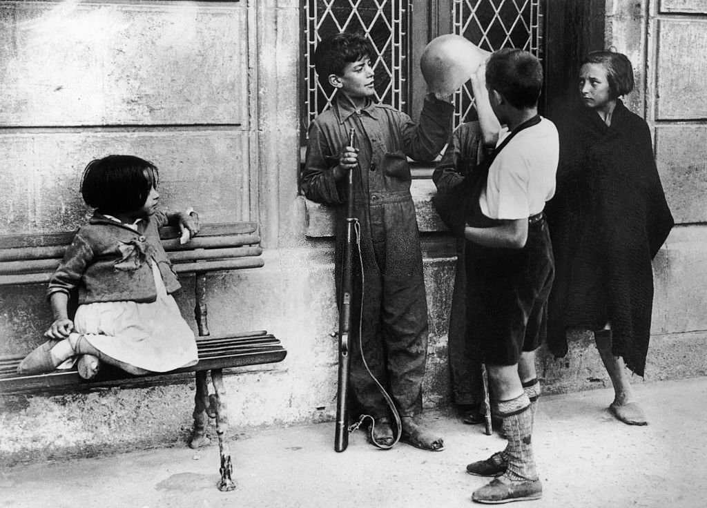 In Burgos during the Spanish civil war, children are admiring the helmet and rifle of the elder brother, signed-up in Franco's troops.