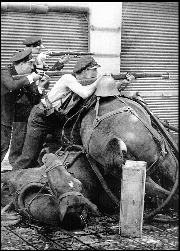 Republican fighters take aim behind a barricade of a dead horses in a street in Barcelona 1937, during the Spanish Civil war.