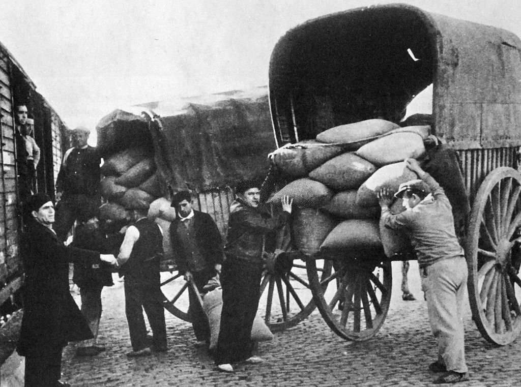 Grain supplies are transferred from carts to rail trucks for distribution during the Spanish Civil War 1936.