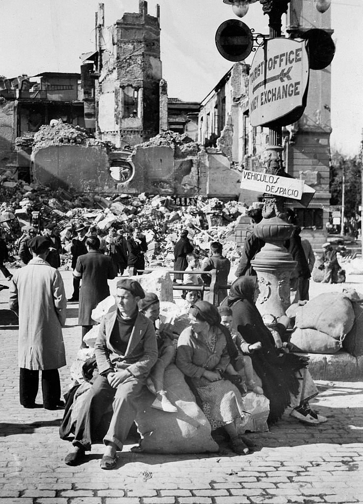 Spanish Civil War Refugees sitting on their belongings in front of a ruined building after the capture of the city by the Nationalists on 7 February 1937