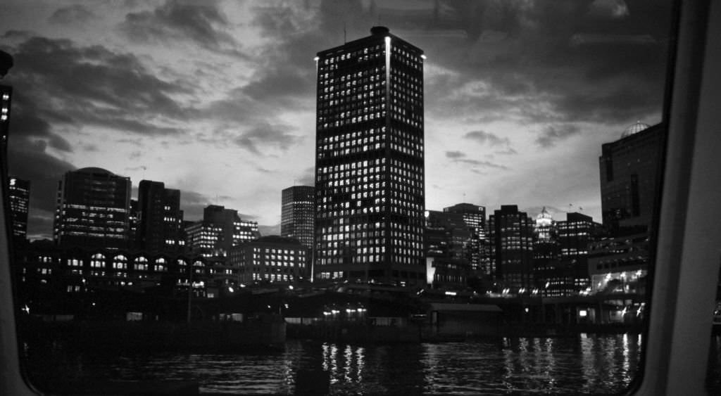 Illuminated buildings at night reflecting off the surface of the Fraser River