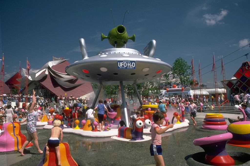 Children play on brightly colored playground equipment that sprays water at the 1986 World's Fair in Vancouver.