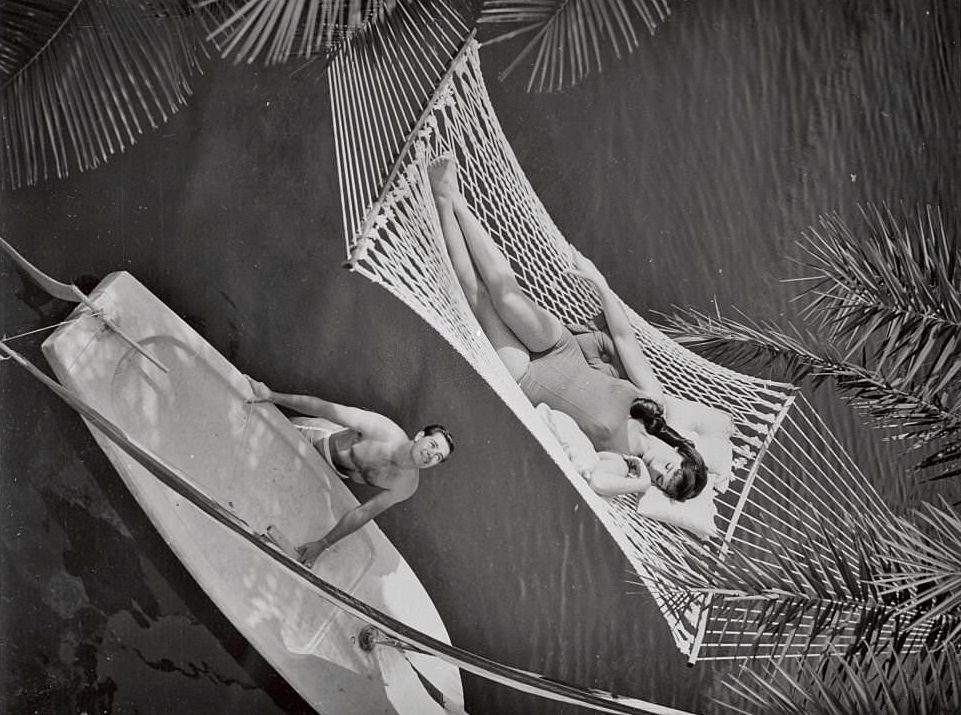 Woman in Hammock Being Gazed Upon by Man with Sailboat at Cypress Gardens, Florida.