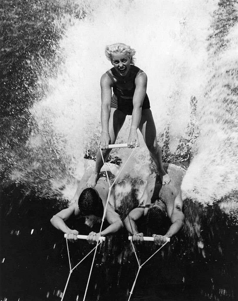 Barbara Clack skis on human water-skis, Joker Osborn and Ken White, champion skiers at Cypress Gardens, Florida, 1973