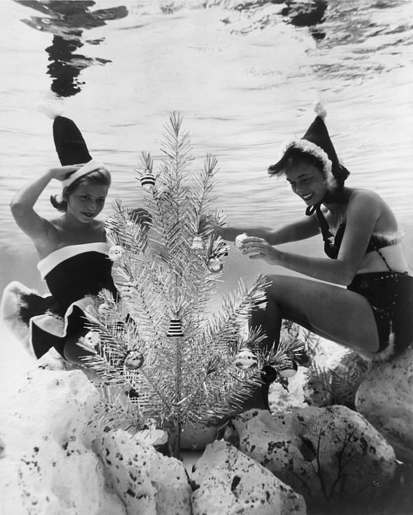 Two of Santa's more alluring helpers decorate an underwater Christmas tree in a pool at Cypress Gardens, Florida, 1968