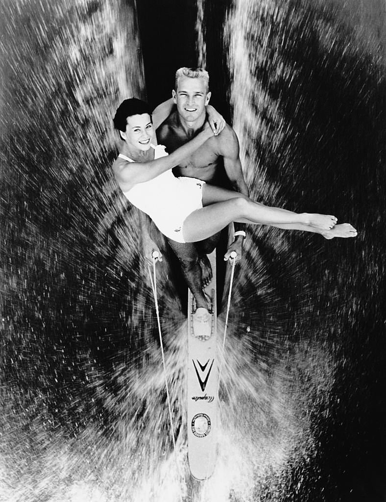 Champion skier Buster MacCalla carries his wife Betty Howard MacCalla in his arms whilst waterskiing on a single ski in Cypress Gardens, Florida, 19th July 1965.