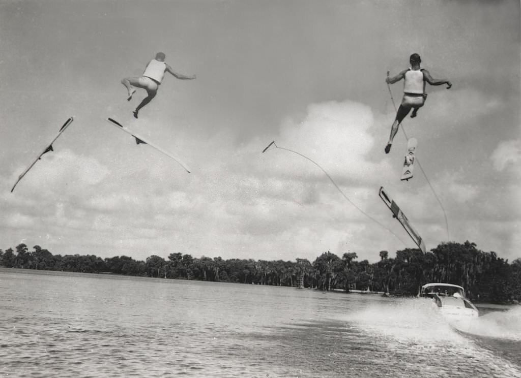 Two professional water-skiers lose their skis, and flounder helplessly in mid-air, during a competition at Cypress Gardens, Florida, 1965