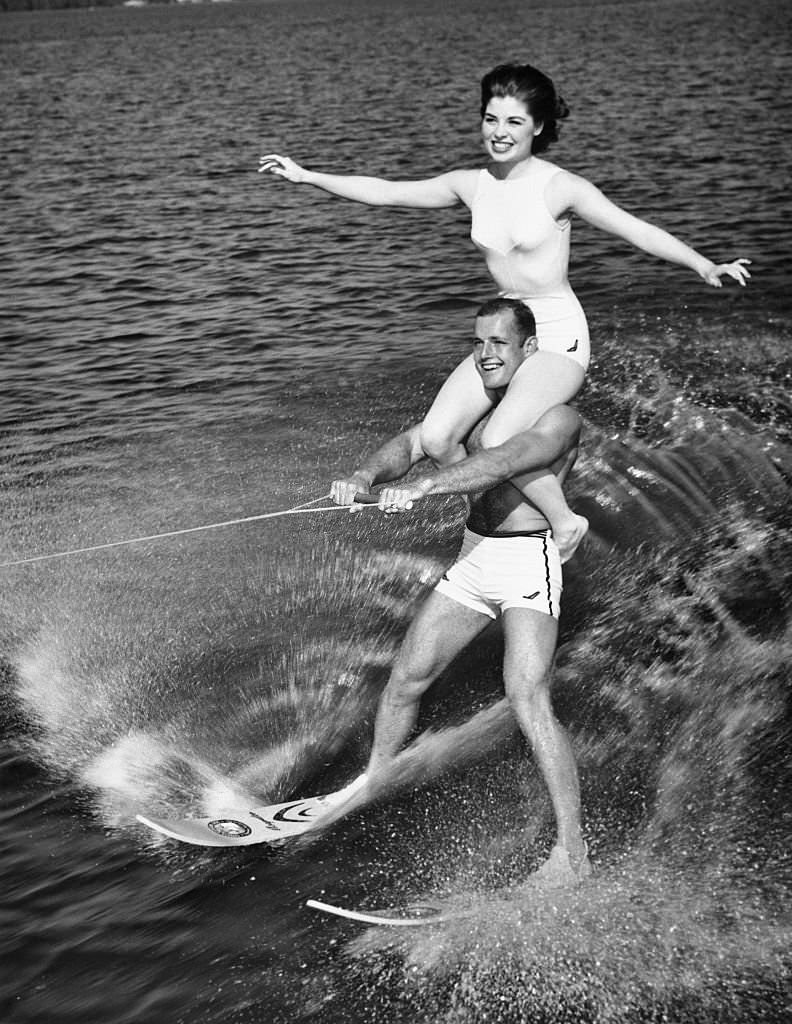 Donna Axum, Miss America of 1964, rides on the shoulders of water skiing champion Don Seyez as they perform the "doubles act" at Cypress Gardens, Florida. June 23, 1964.