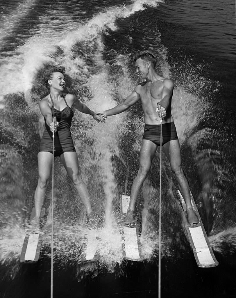 Water-ski champions Dick Pope and Jean Mason prepare to transfer from four skis to one as they speed across the course at the US Ski Centre at Cypress Gardens, 1963.