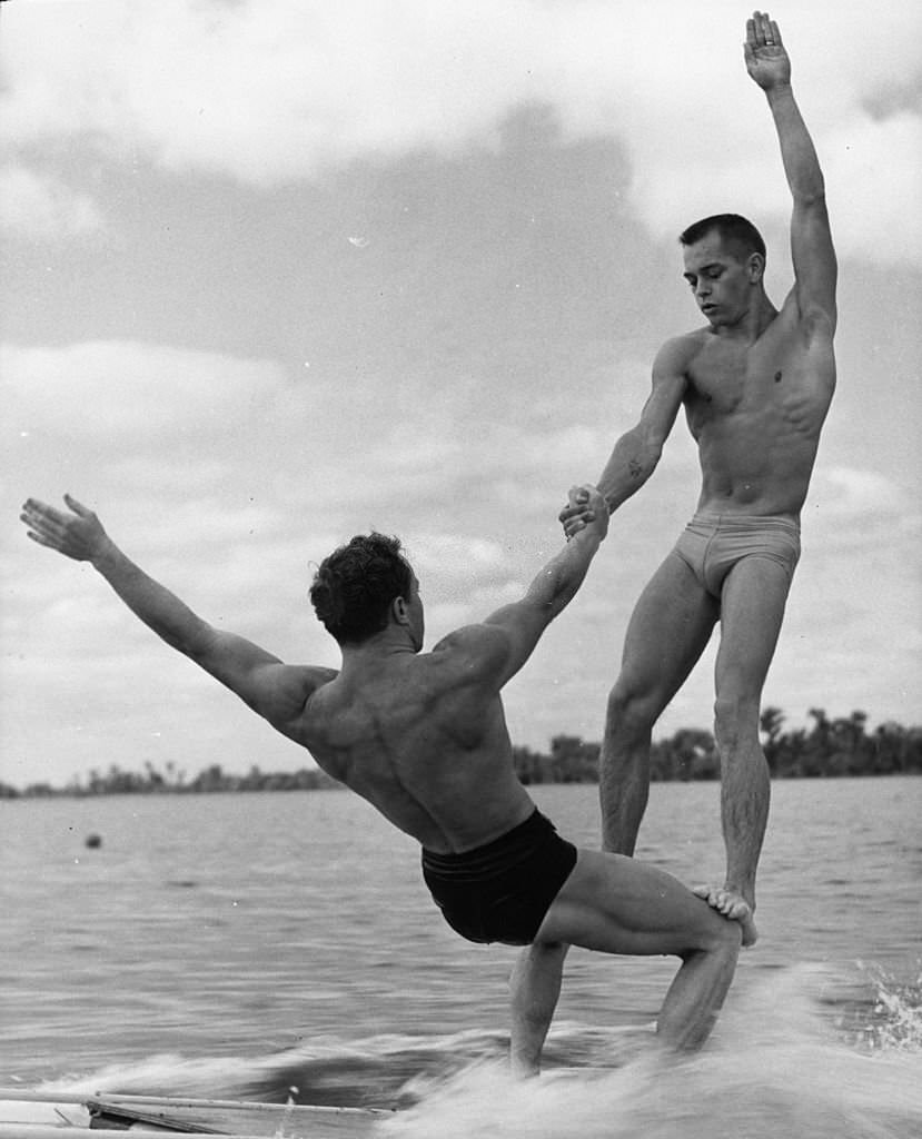 Two athletes practising a gymnastic 'aqua acrobatic' exercise on a water toboggan at Cypress Gardens, Florida, 1963