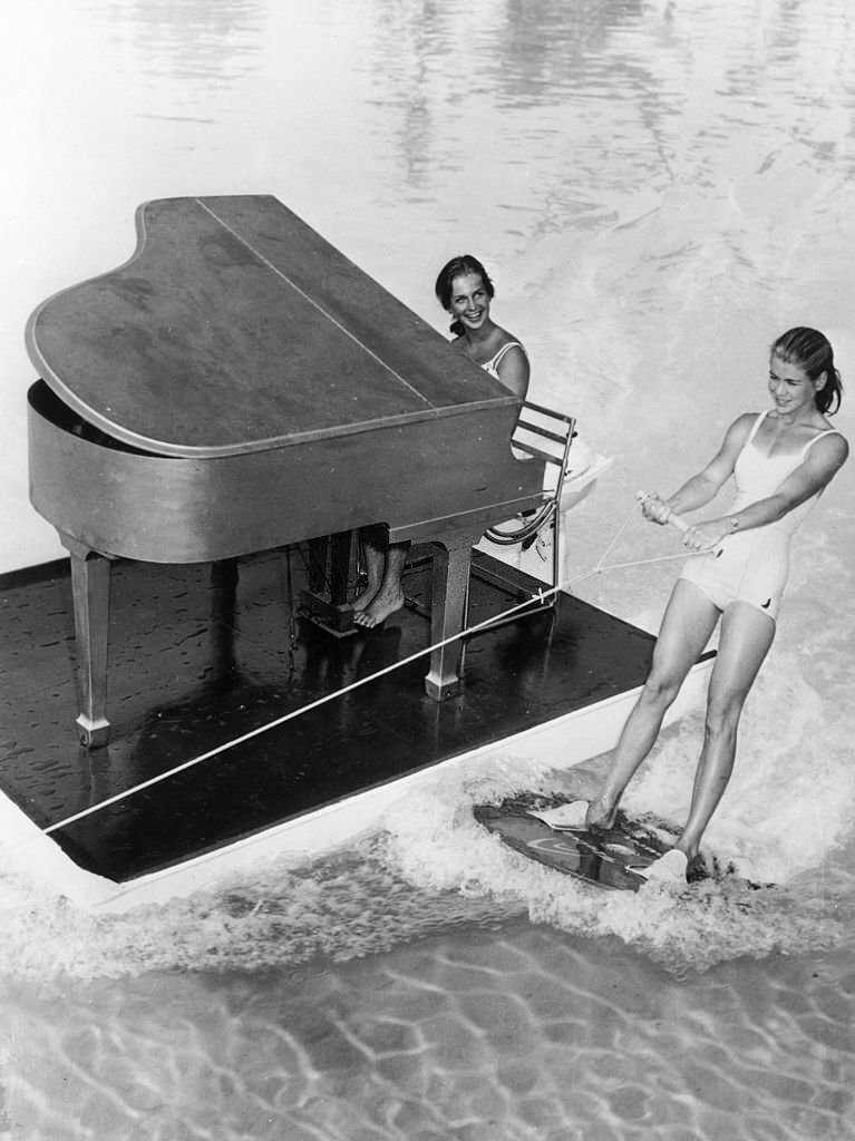 A floating piano and pianist accompany a water-skier on Lake Eloise at Cypress Gardens in Florida, 1962