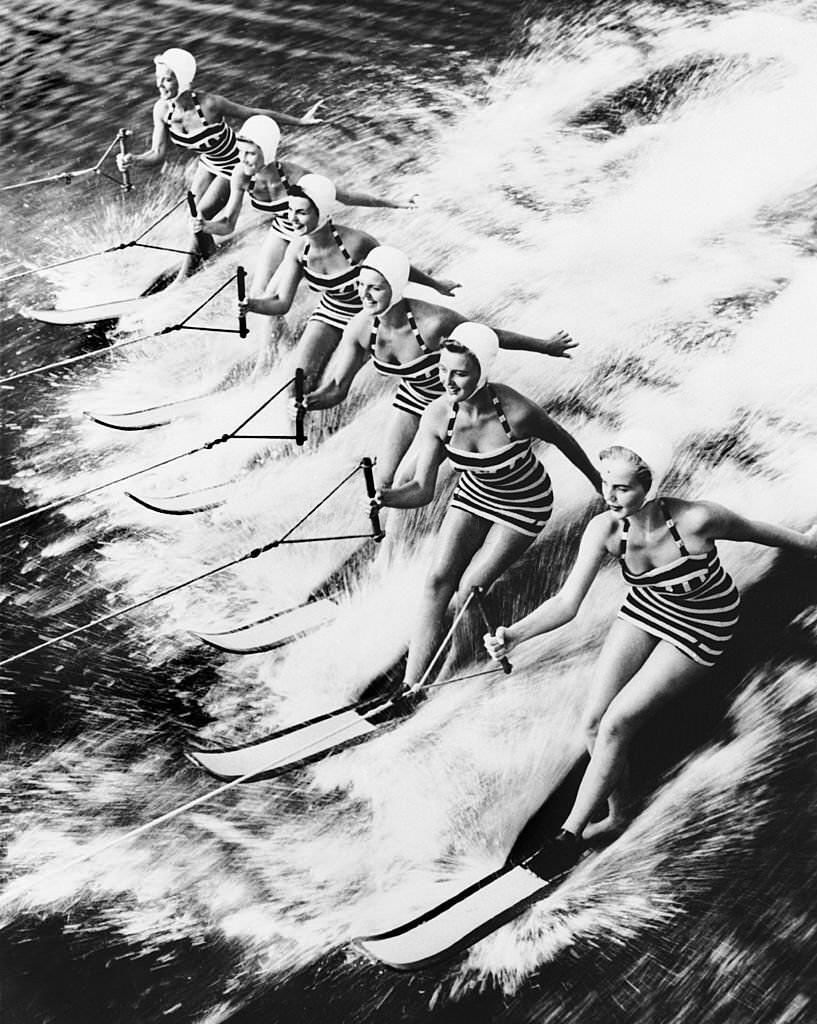 These young women sliding together on water in Cypress Gardens, Florida, where visitors could attend water shows, especially water-skiing exhibitions.