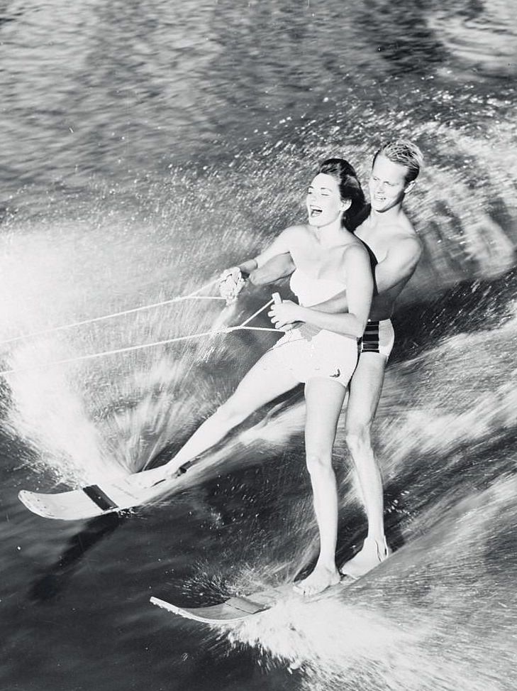 Pretty Pat Johnson of Inglewood, California, is a welcome passenger aboard Roger Wises's water skis, as they cut through the water at Cypress Gardens, 1950s