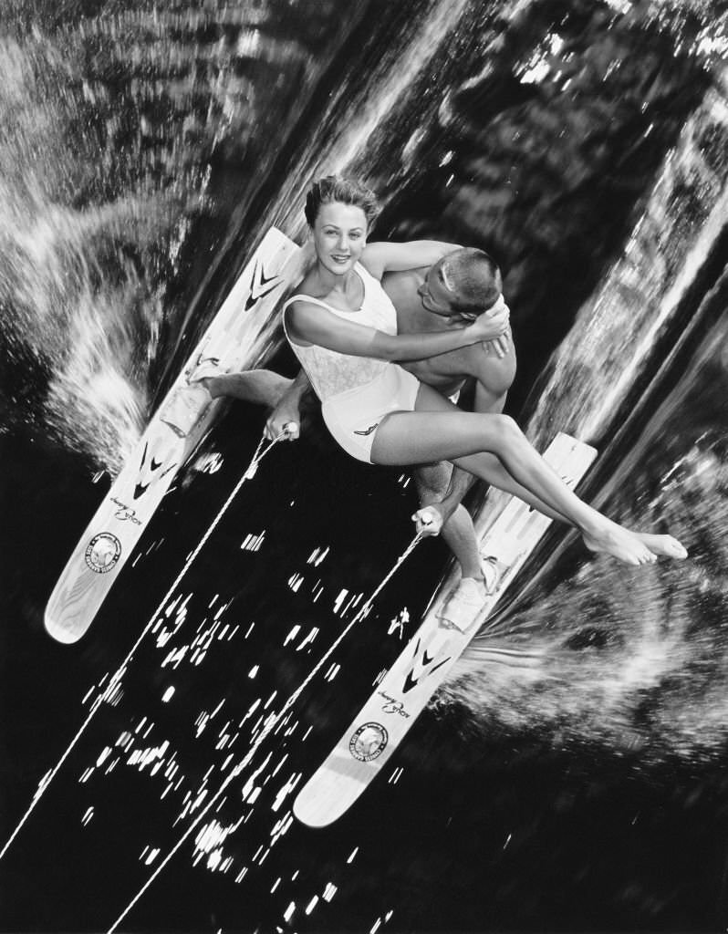 A man carries a woman in his arms whilst waterskiing at Cypress Gardens in Florida, 1955.