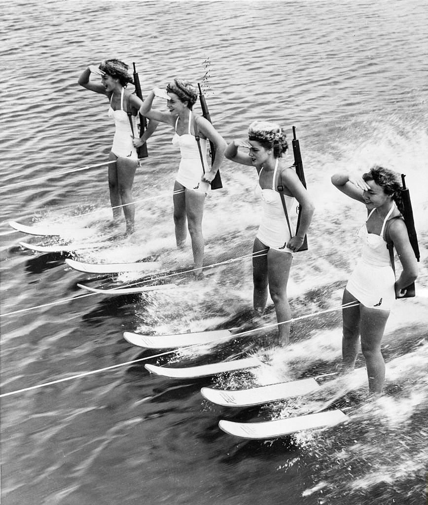 four women on water skis: they wear bearskin hats and rifles at Cypress Gardens, 1955