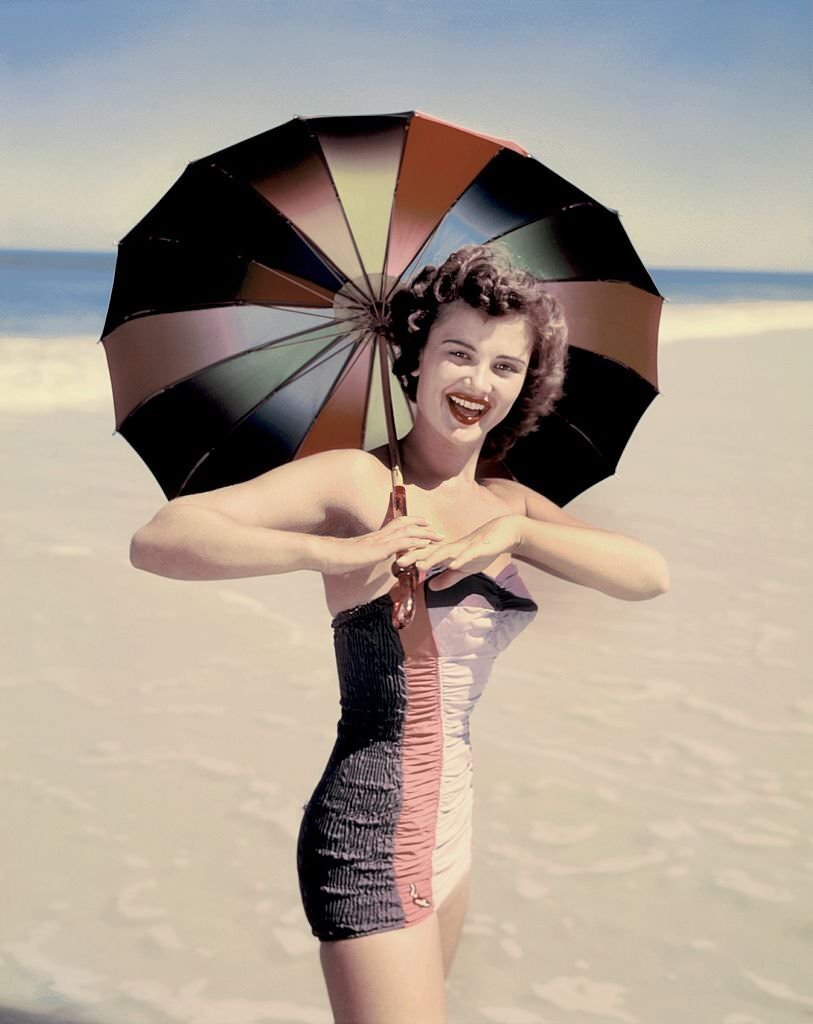 A southern belle model poses with a parasol on the beach at Cypress Gardens theme park in 1953 near Winterhaven, Florida.