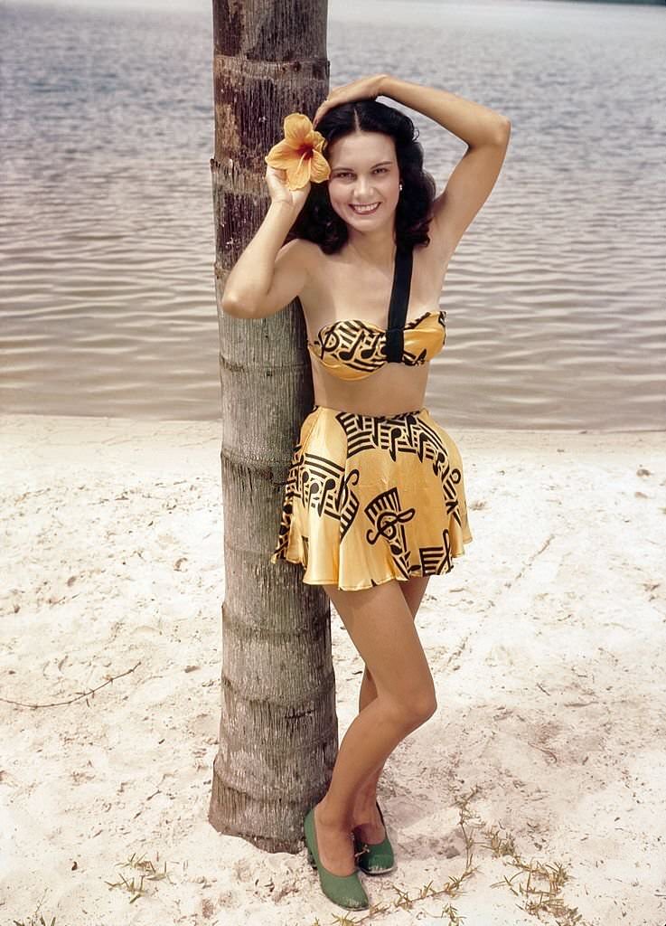 A southern belle model poses by a Palm tree on the beach at Cypress Gardens theme park in 1953 near Winterhaven, Florida.