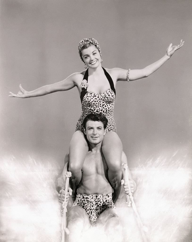 Ski Team. Esther Williams sits atop John Bromfield's shoulders to water-ski for movie 'Easy to Love'.