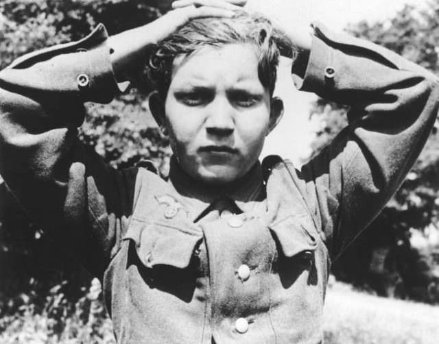 A 16-year old German soldier has his hands clasped over his head as he is taken prisoner with thousands of other Wehrmacht soldiers, at Cherbourg, France, during the Allied Normandy invasion in June 1944