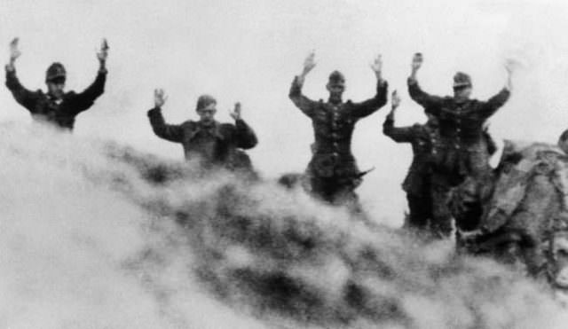 German soldiers, former Herrenvolk, come over the crest of a hill with their hands over their heads in surrender to American troops during the battle for the Norman beachhead in France on June 11, 1944.