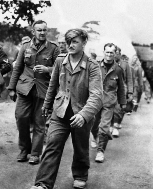 A column of German prisoners, captured in fighting for the outer defenses of Cherbourg are marched to a prisoner of war stockade behind the lines on June 29, 1944.