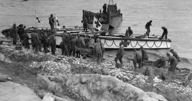 German prisoners help evacuate some of their own wounded, and are seen being put on board Red Cross boats to be taken out to the mother ship, standing by off the beachhead area in Normandy, France on June 10, 1944.