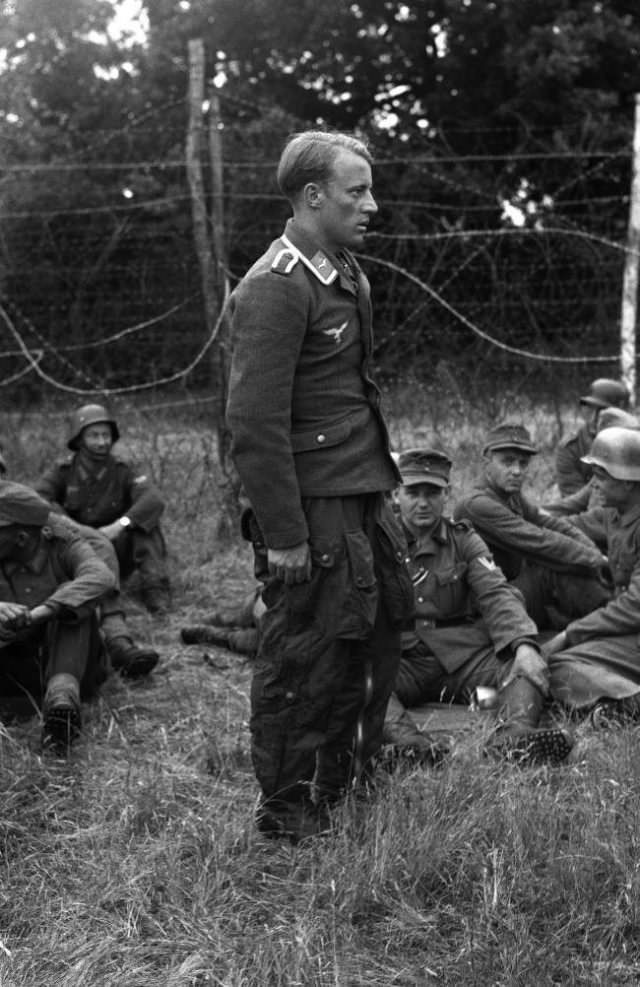 The first Nazi airman to be shot down in the invasion area stands dejected amongst other prisoners at a camp somewhere in England, on June 9, 1944.