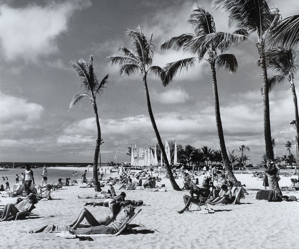 A packed beach with people sunbathing and enjoying the sea, 1970s