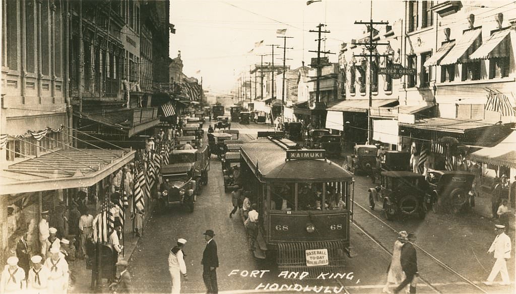 High angle shot of city street with trolley cars, American flags and sailors, 1940s