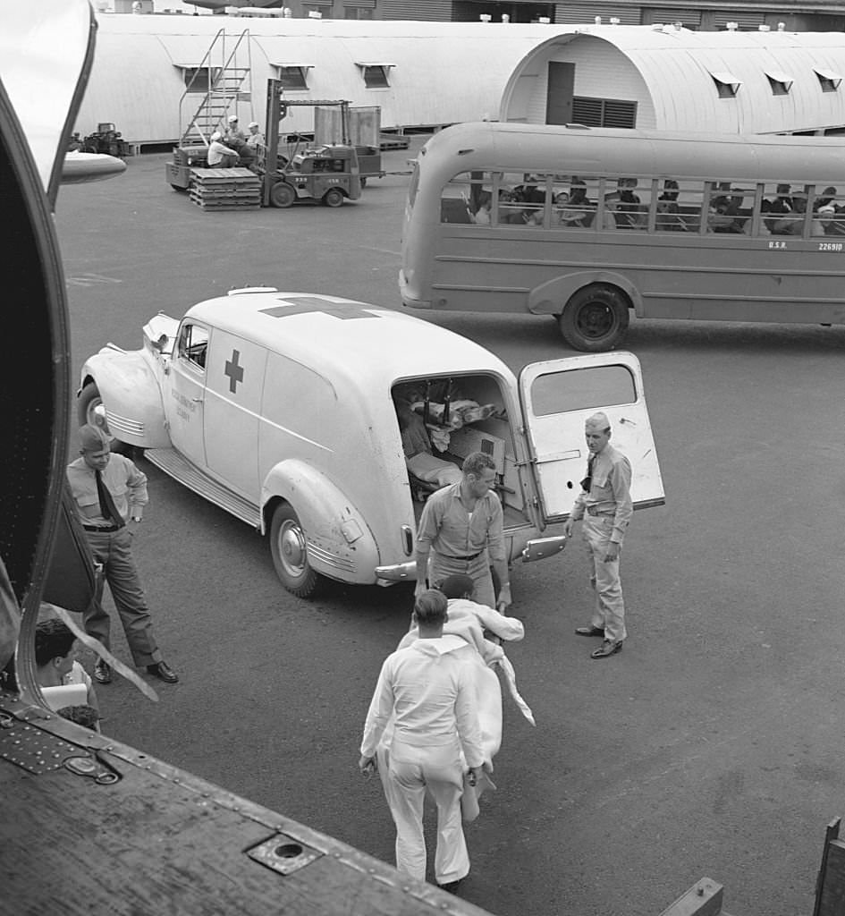 A wounded POW is unloaded from a transport plane to a Red Cross ambulance in Honolulu. October 1945.