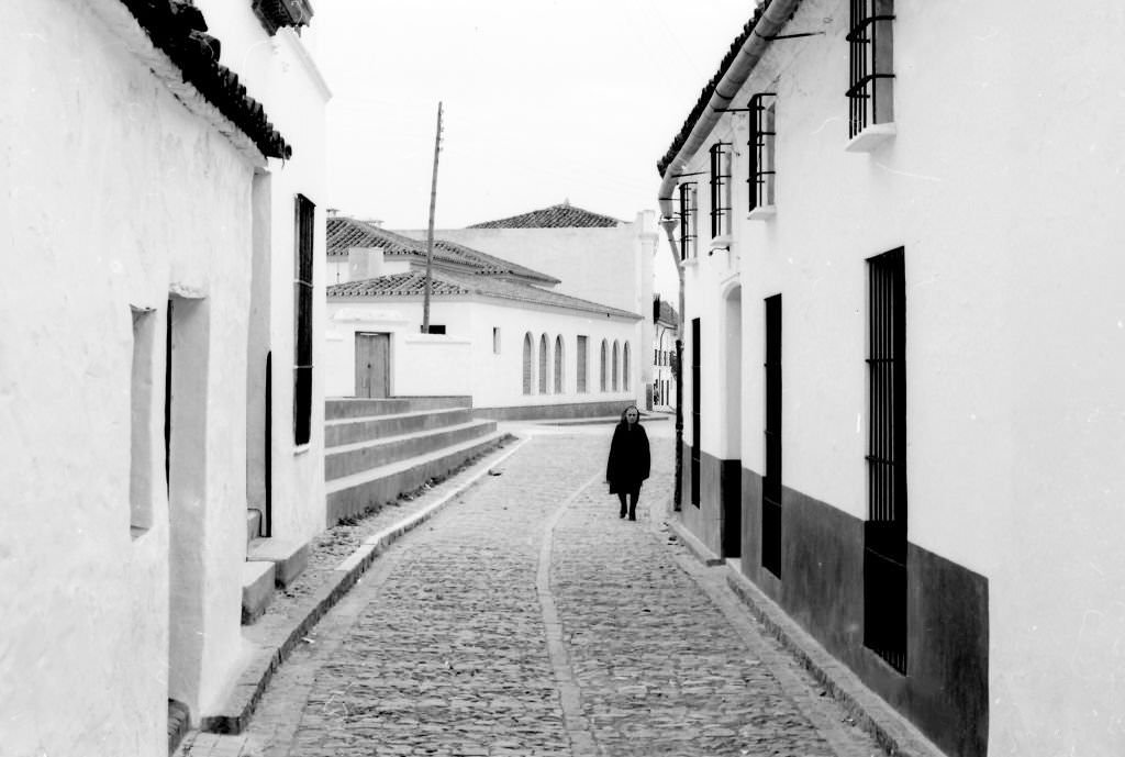 The lonely walk of an old woman in a deserted street in the small town of Fuente de los Cantos, Badajoz, Extremadura, 1964.