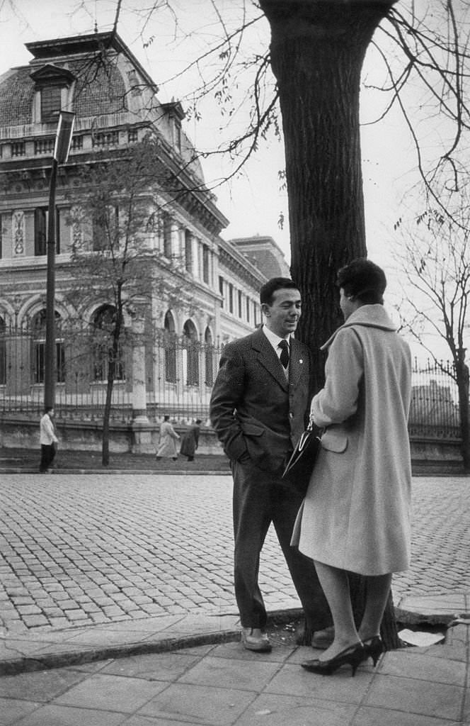 A man and a woman chatting beside a tree. Madrid, May 1960